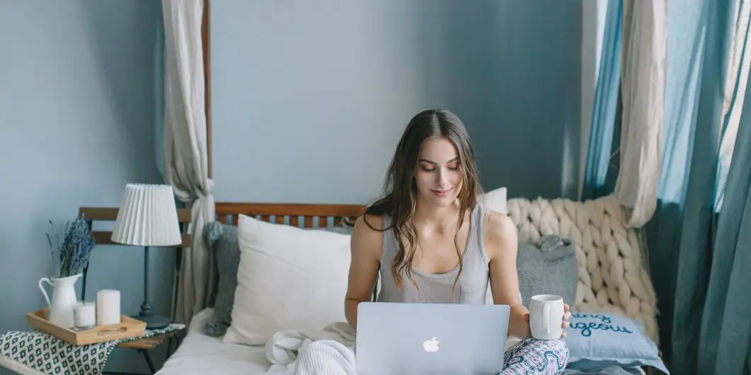 woman on bed with laptop Christian social media marketing planner