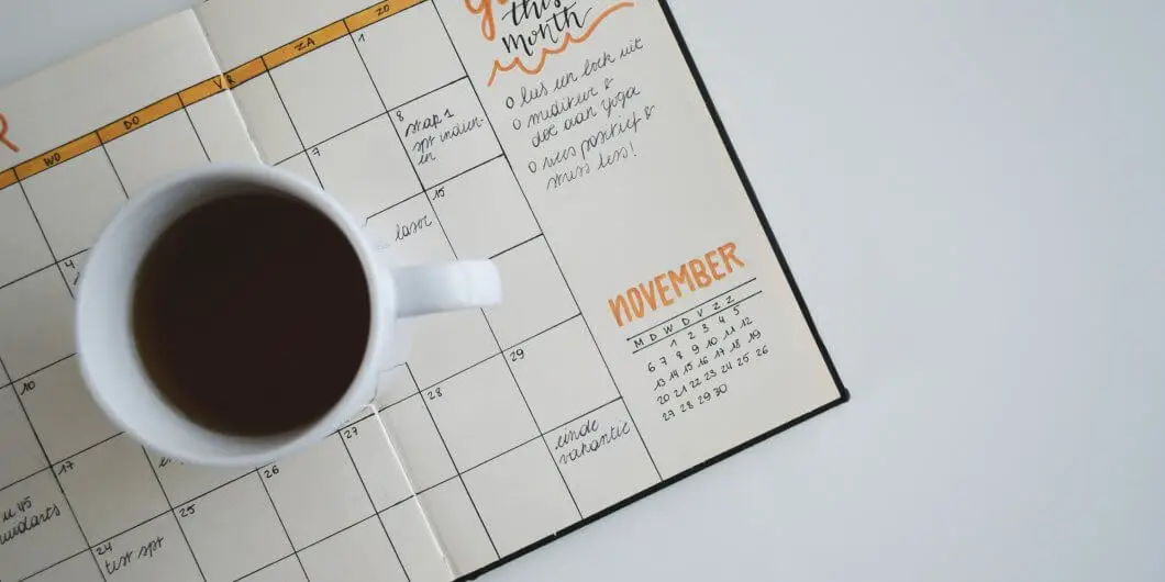 a blogging goals planner on a white desk with a cup of coffee on top